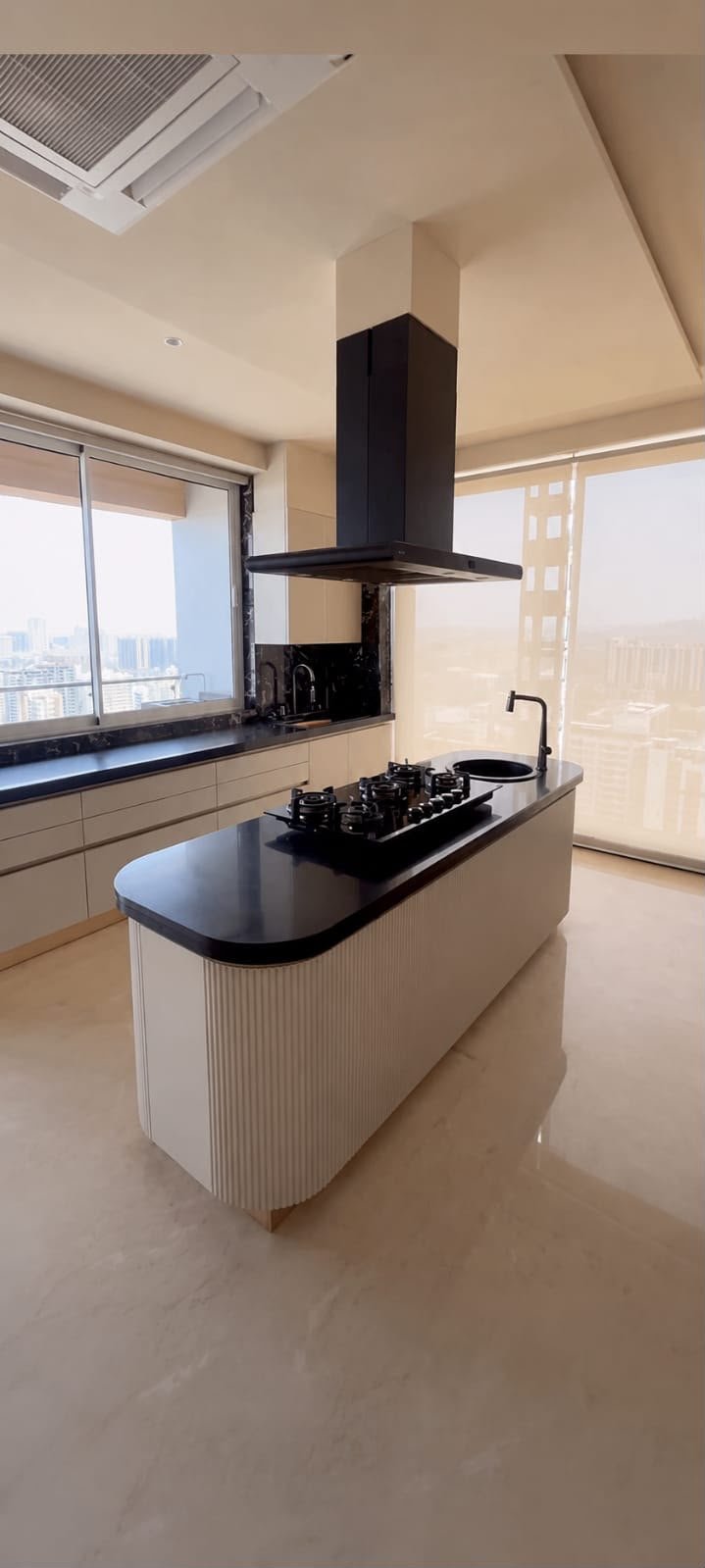 Kitchen island with chimney hood near a window